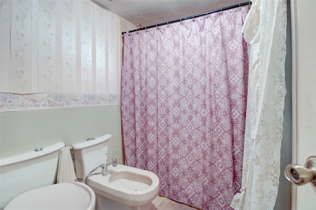 bathroom featuring a bidet, toilet, and wallpapered walls