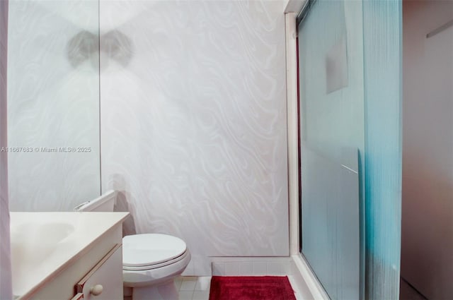 bathroom featuring toilet, a shower stall, vanity, and tile patterned floors