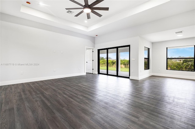 unfurnished room with dark hardwood / wood-style floors, a raised ceiling, and ceiling fan