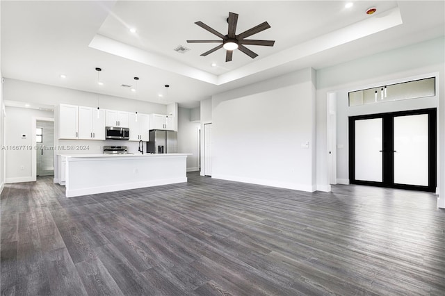 kitchen featuring a kitchen island, white cabinets, hanging light fixtures, and a tray ceiling