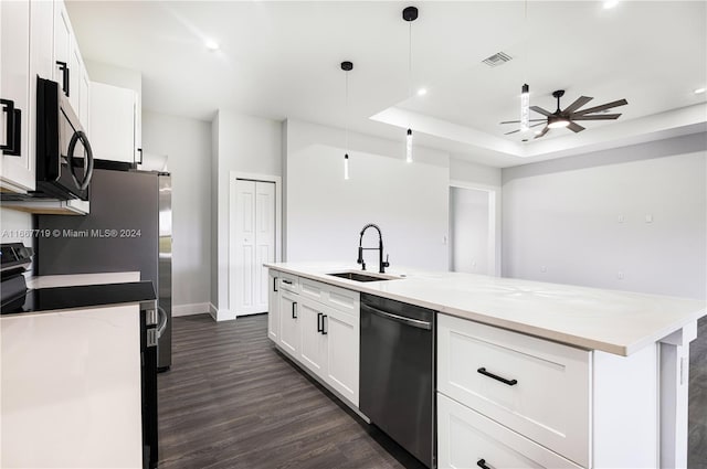 kitchen featuring appliances with stainless steel finishes, sink, an island with sink, white cabinetry, and decorative light fixtures