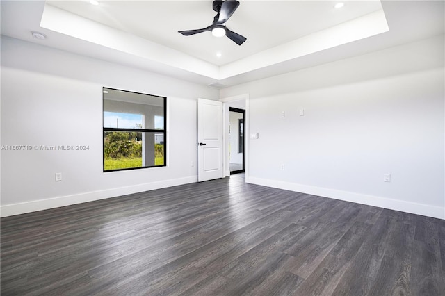 unfurnished room featuring ceiling fan, a raised ceiling, and dark hardwood / wood-style floors