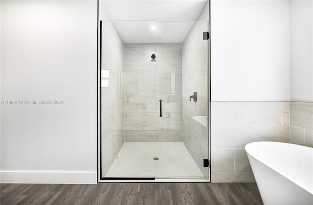 bathroom with shower with separate bathtub, hardwood / wood-style flooring, and tile walls