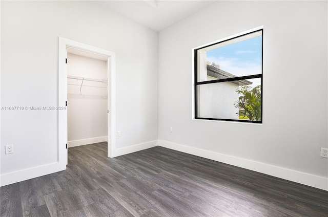 unfurnished bedroom featuring a spacious closet, a closet, and dark hardwood / wood-style flooring