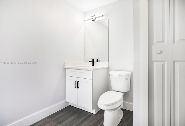 bathroom with toilet, hardwood / wood-style floors, and vanity