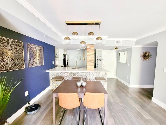 dining room with hardwood / wood-style flooring, sink, and crown molding