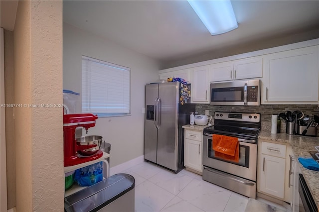 kitchen with white cabinets, stainless steel appliances, backsplash, and light stone countertops