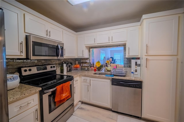 kitchen featuring white cabinetry, light stone countertops, and stainless steel appliances