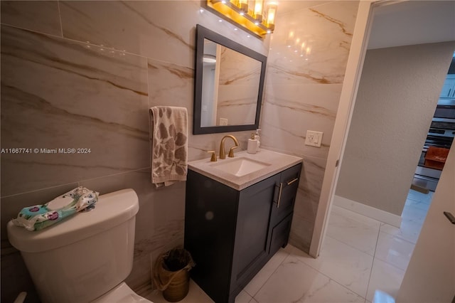 bathroom with tile walls, vanity, and toilet