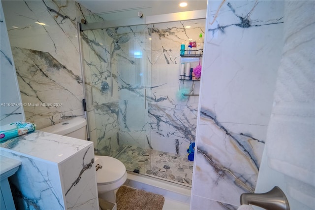 bathroom featuring tile walls, vanity, a shower with shower door, and toilet