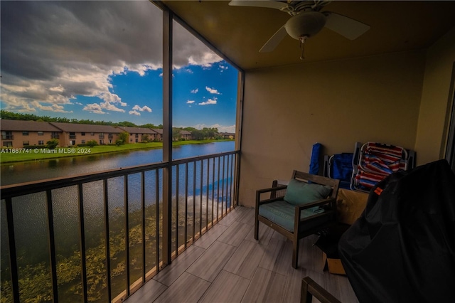 balcony at dusk featuring a water view and ceiling fan