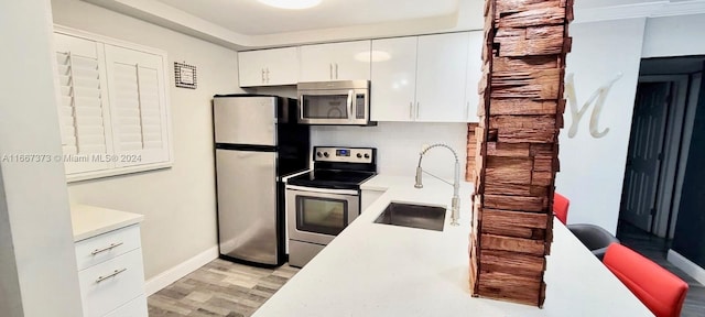 kitchen with tasteful backsplash, stainless steel appliances, white cabinetry, sink, and light hardwood / wood-style floors