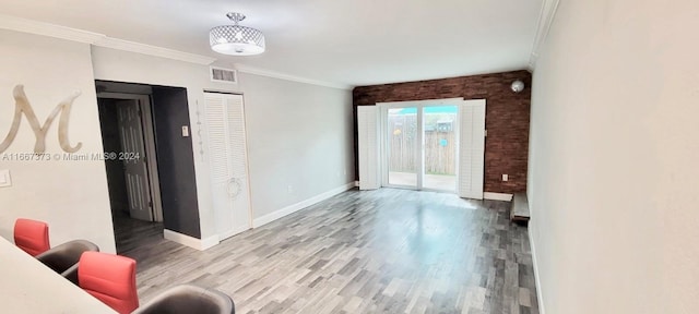 unfurnished room featuring ornamental molding, light wood-type flooring, and brick wall