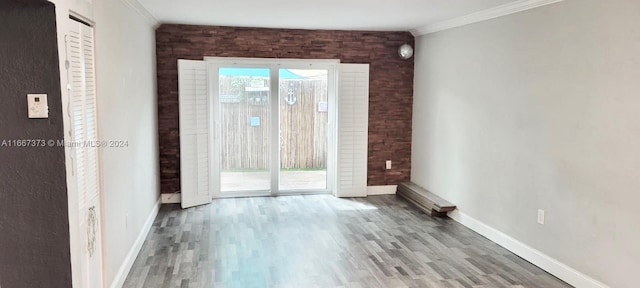 empty room featuring ornamental molding, hardwood / wood-style floors, and brick wall