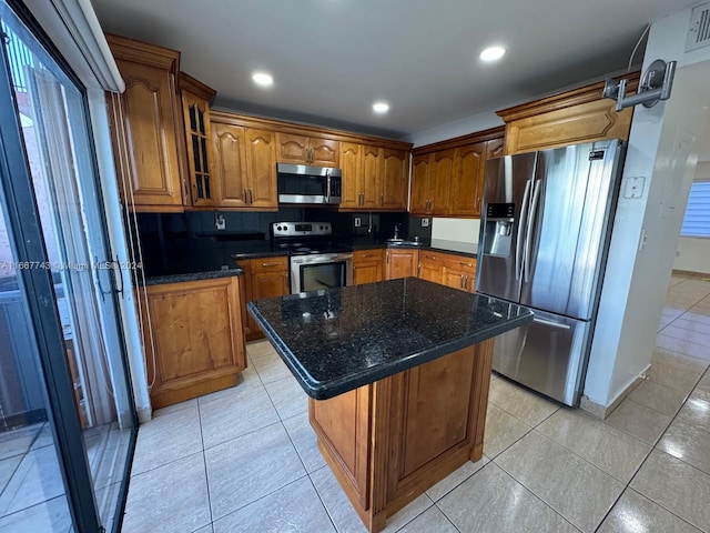 kitchen featuring a center island, stainless steel appliances, tasteful backsplash, and dark stone countertops