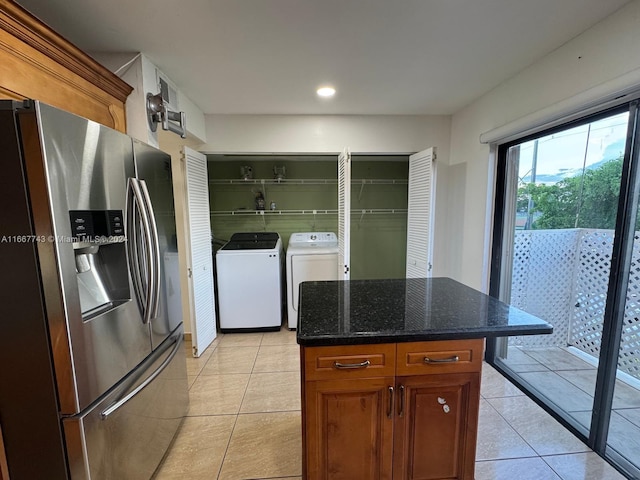 kitchen with dark stone countertops, stainless steel fridge, a center island, separate washer and dryer, and light tile patterned floors