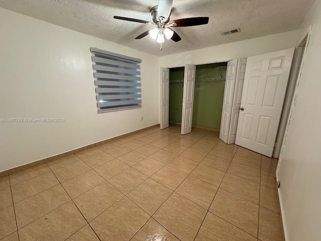 unfurnished bedroom featuring a textured ceiling, light tile patterned floors, and ceiling fan