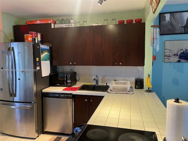 kitchen featuring sink, dark brown cabinets, appliances with stainless steel finishes, tile counters, and decorative backsplash