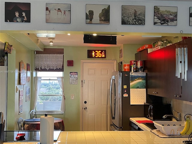 kitchen with tile countertops, stainless steel fridge, and kitchen peninsula