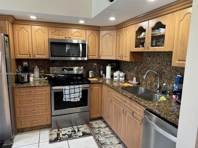 kitchen featuring dark stone countertops, tasteful backsplash, light tile patterned floors, stainless steel appliances, and sink