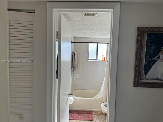 bathroom with toilet and shower / bath combo with shower curtain