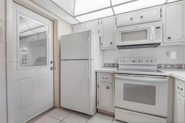 kitchen with white appliances, white cabinetry, light tile patterned flooring, and tasteful backsplash