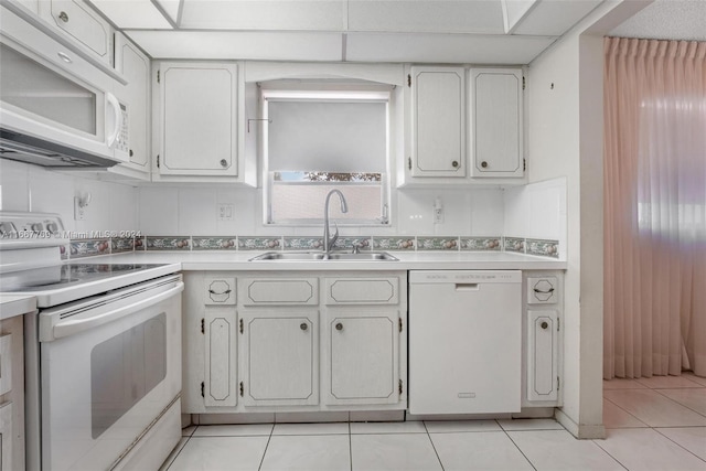 kitchen featuring white appliances, white cabinetry, sink, and tasteful backsplash