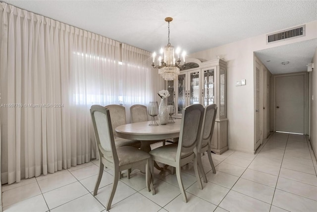 tiled dining area with a textured ceiling and a notable chandelier