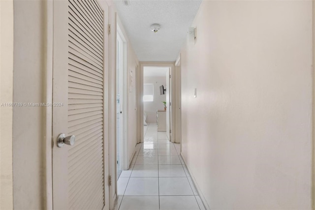 corridor with a textured ceiling and light tile patterned floors