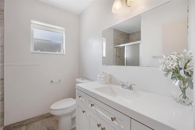 bathroom with walk in shower, vanity, and toilet