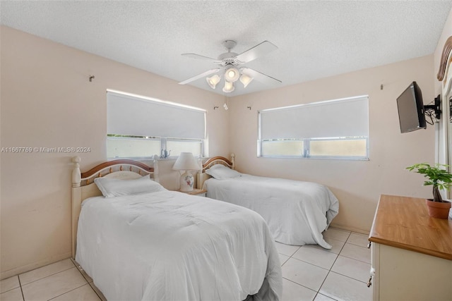 bedroom featuring ceiling fan, light tile patterned floors, and a textured ceiling