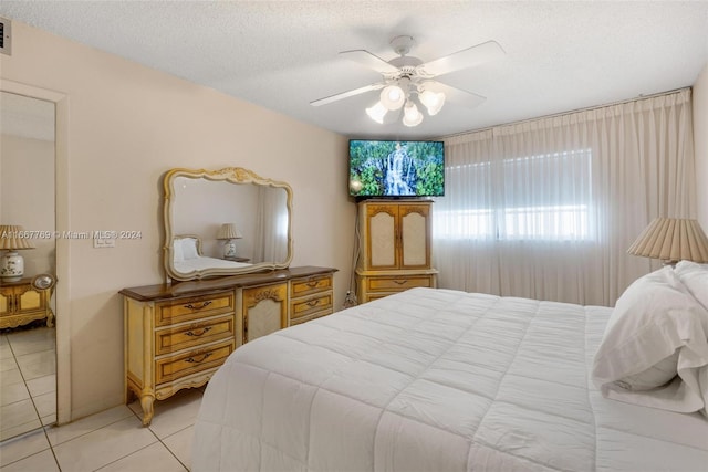 tiled bedroom with ceiling fan and a textured ceiling