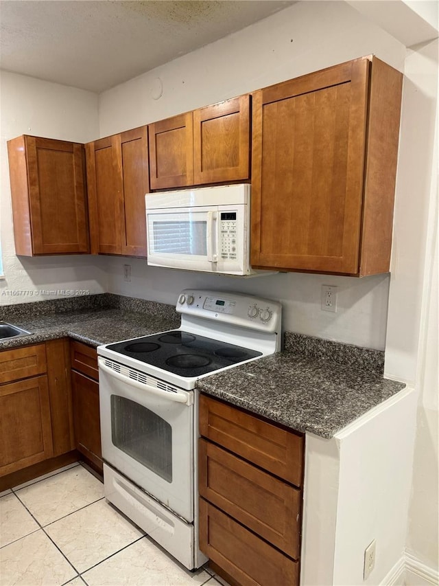 kitchen with light tile patterned floors, a textured ceiling, and white appliances