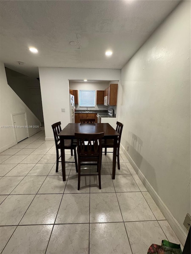 tiled dining space with sink and a textured ceiling