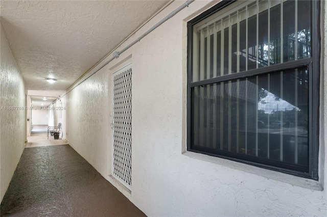 corridor with a textured ceiling and crown molding