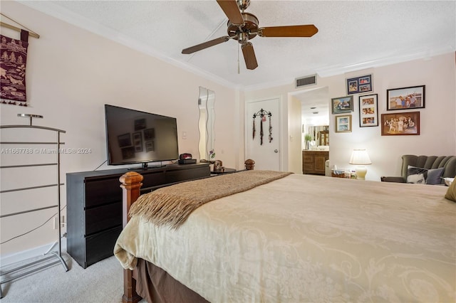 bedroom featuring ceiling fan, ornamental molding, a textured ceiling, carpet, and ensuite bath