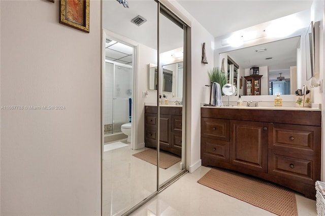 bathroom featuring tile patterned flooring, a shower with door, vanity, and toilet