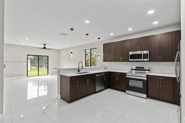 kitchen with stainless steel appliances, kitchen peninsula, a healthy amount of sunlight, and sink