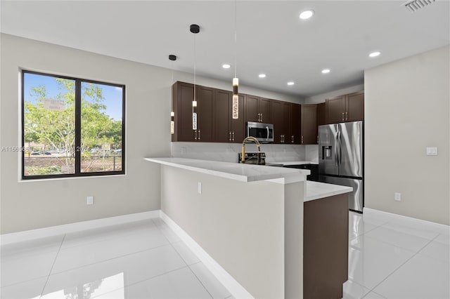 kitchen featuring pendant lighting, light tile patterned floors, kitchen peninsula, tasteful backsplash, and stainless steel appliances