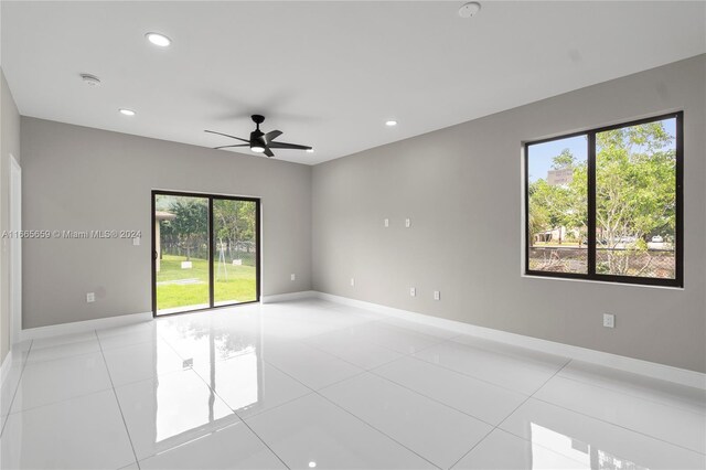 tiled empty room featuring a healthy amount of sunlight and ceiling fan