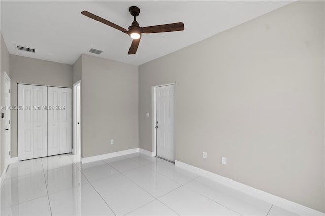 unfurnished bedroom with light tile patterned flooring, ceiling fan, and a closet