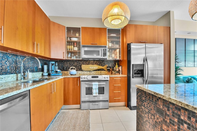 kitchen with appliances with stainless steel finishes, light stone countertops, backsplash, and sink