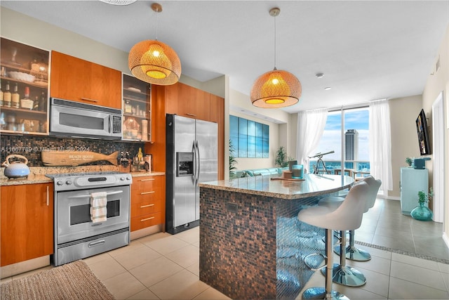 kitchen with appliances with stainless steel finishes, light tile patterned flooring, pendant lighting, and tasteful backsplash