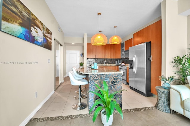 kitchen featuring appliances with stainless steel finishes, decorative backsplash, light tile patterned flooring, and decorative light fixtures