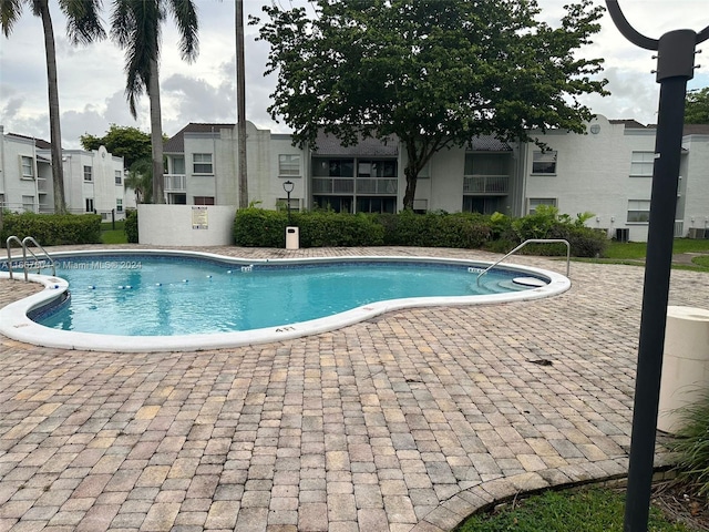 view of swimming pool with central AC unit and a patio