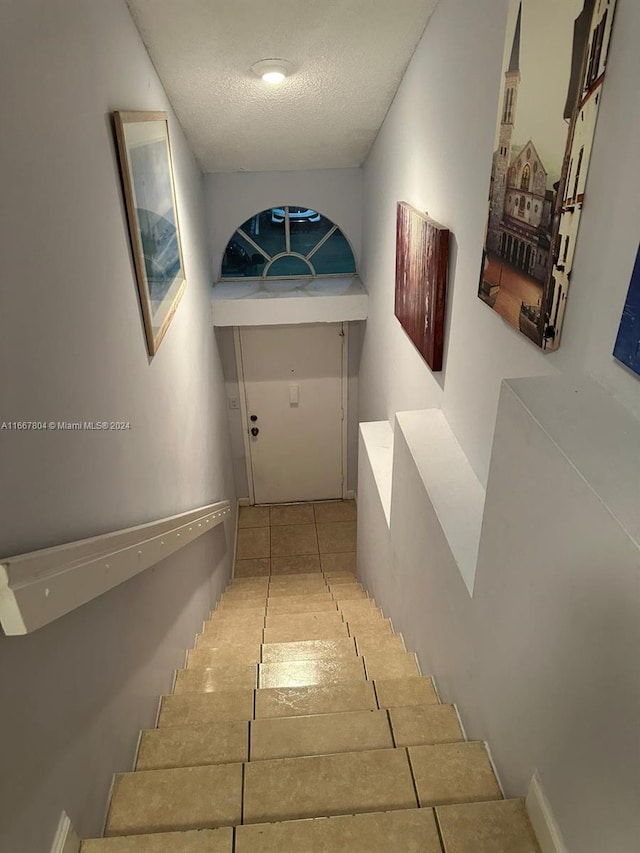 corridor with a textured ceiling and light tile patterned floors