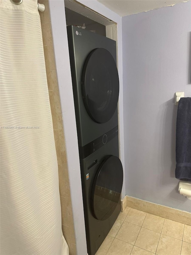 washroom featuring light tile patterned floors and stacked washing maching and dryer