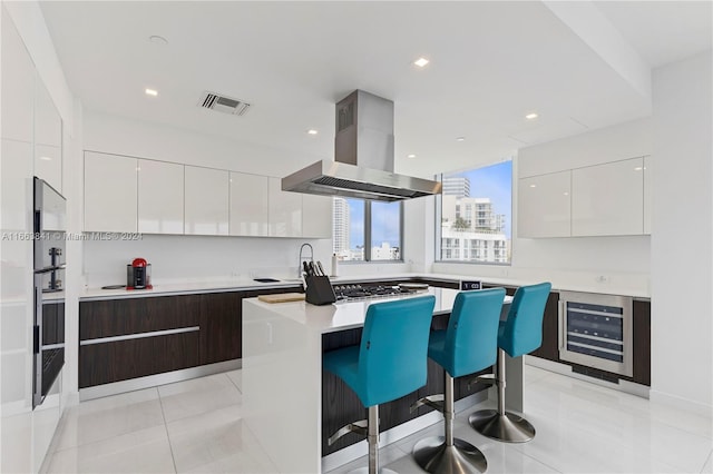 kitchen featuring a breakfast bar area, white cabinets, island range hood, and a kitchen island