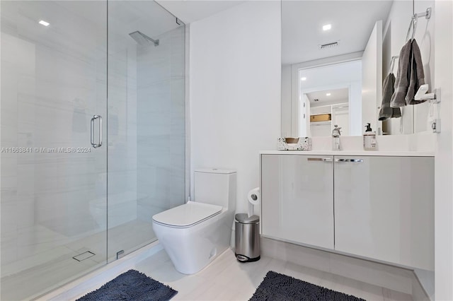 bathroom with an enclosed shower, vanity, toilet, and tile patterned floors