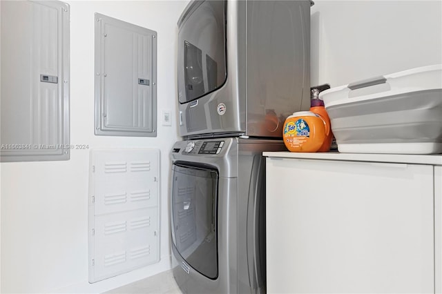 laundry room featuring electric panel and stacked washer and clothes dryer